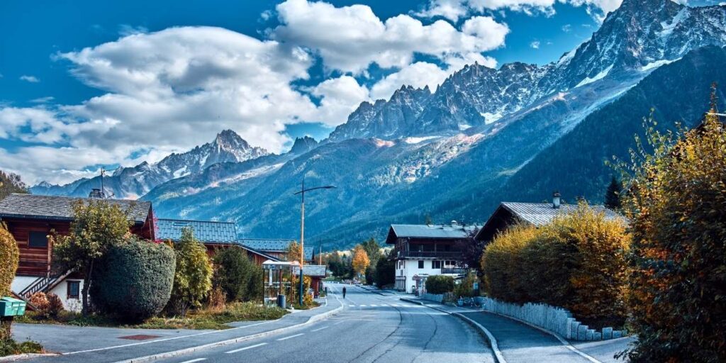 Empty road to the French Alps with mountain view and chalets near Chamonix in autumn