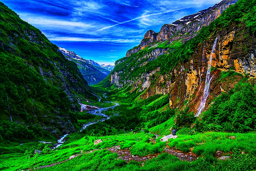 Scenic view of Cirque du Fer-à-Cheval near Samoëns with waterfall, green valley, and mountain peaks in summer